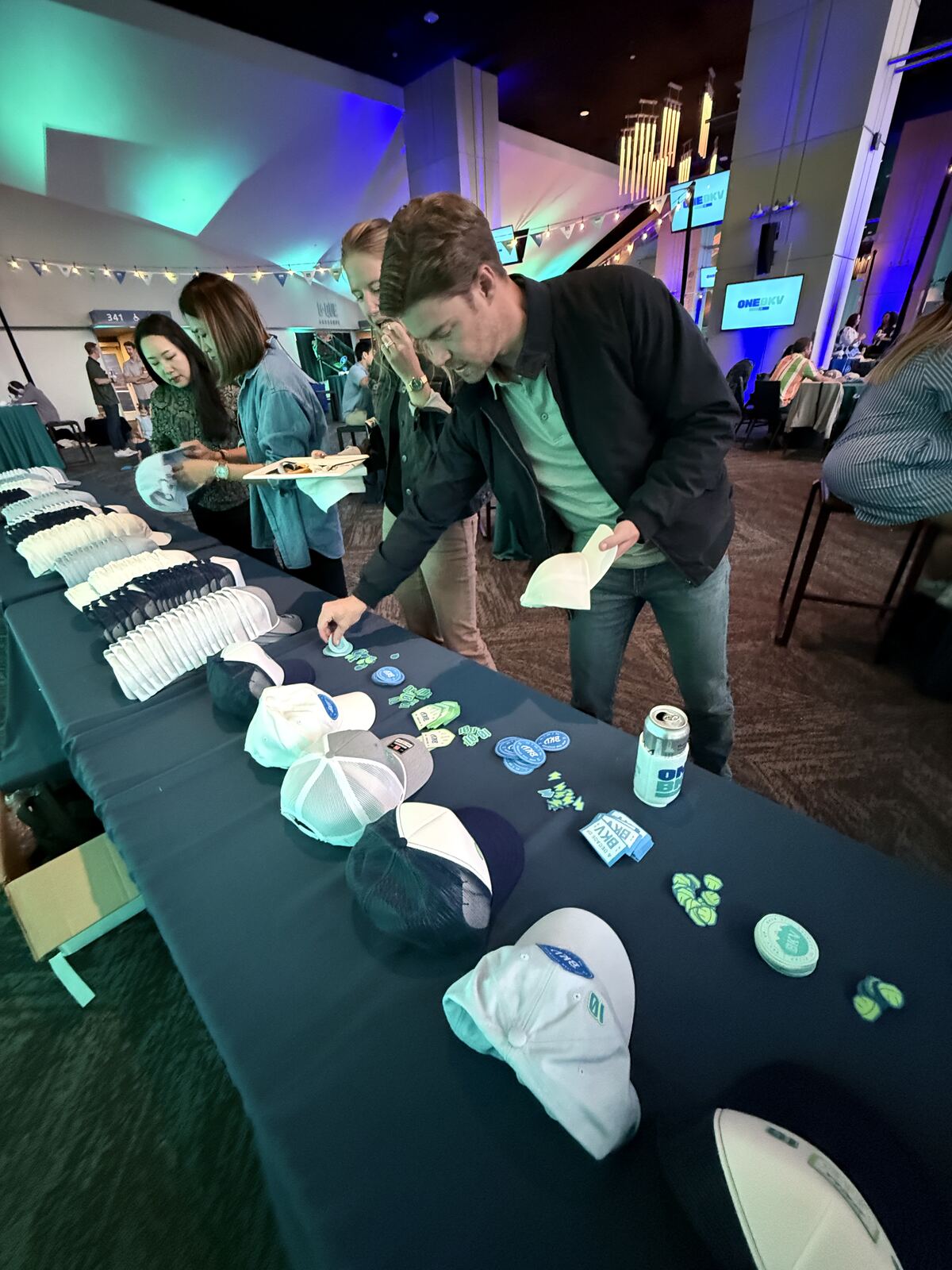 Event booth display featuring decorated hats and apparel with attendees examining products